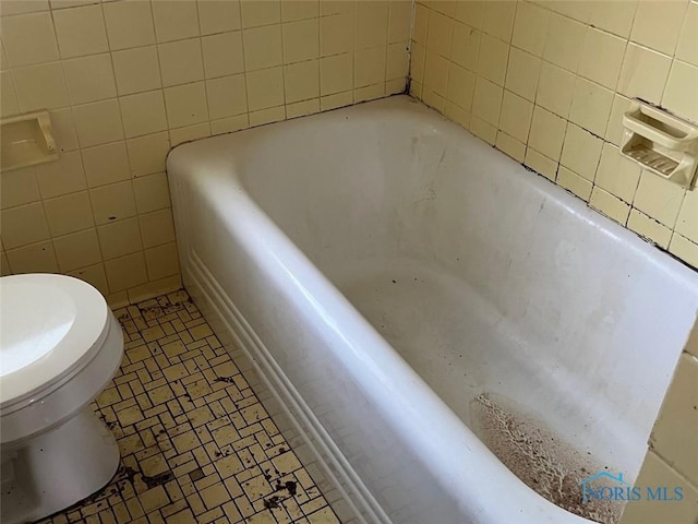 bathroom with toilet, tile walls, and a washtub