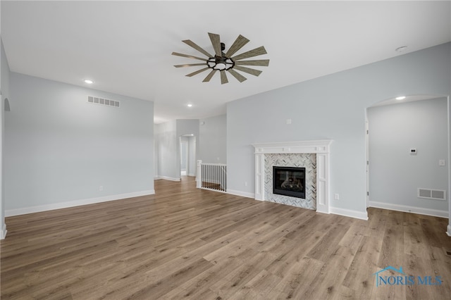 unfurnished living room with a high end fireplace, light hardwood / wood-style floors, and ceiling fan