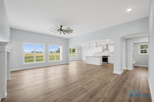 unfurnished living room featuring light hardwood / wood-style floors, ceiling fan, and sink