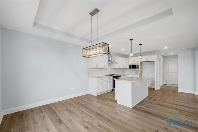 kitchen featuring sink, white cabinets, hanging light fixtures, wall chimney exhaust hood, and appliances with stainless steel finishes