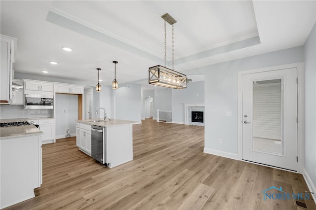 kitchen with white cabinets, pendant lighting, a high end fireplace, stainless steel appliances, and sink