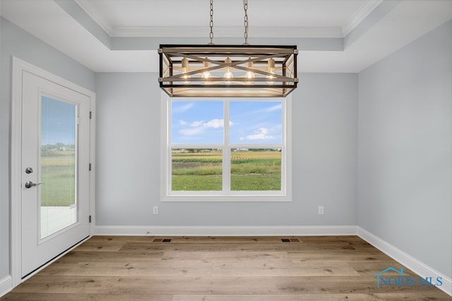 unfurnished dining area featuring crown molding, light hardwood / wood-style floors, and a notable chandelier