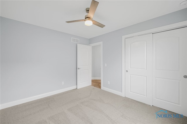 unfurnished bedroom with ceiling fan, a closet, and light carpet