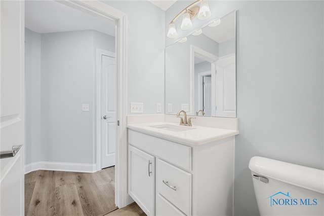 bathroom featuring wood-type flooring, vanity, and toilet