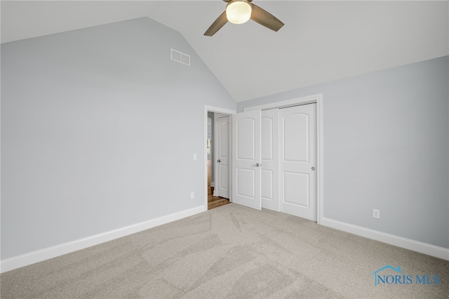 unfurnished bedroom featuring light carpet, a closet, lofted ceiling, and ceiling fan