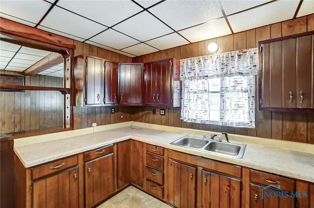 kitchen featuring light tile patterned floors, wooden walls, and sink