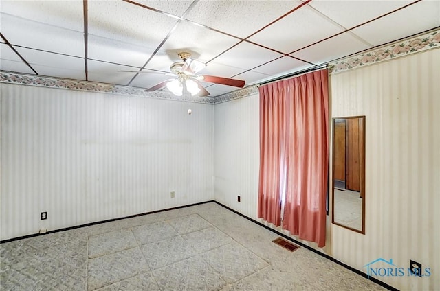 empty room featuring ceiling fan and a paneled ceiling