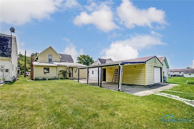 back of property with a lawn, a carport, and a garage