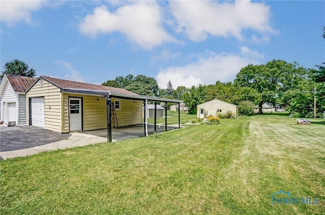 view of yard with a garage, an outbuilding, and a carport