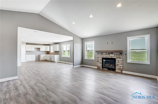 unfurnished living room with a fireplace, vaulted ceiling, and wood-type flooring