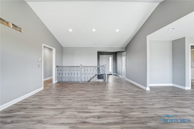 empty room featuring high vaulted ceiling and wood-type flooring