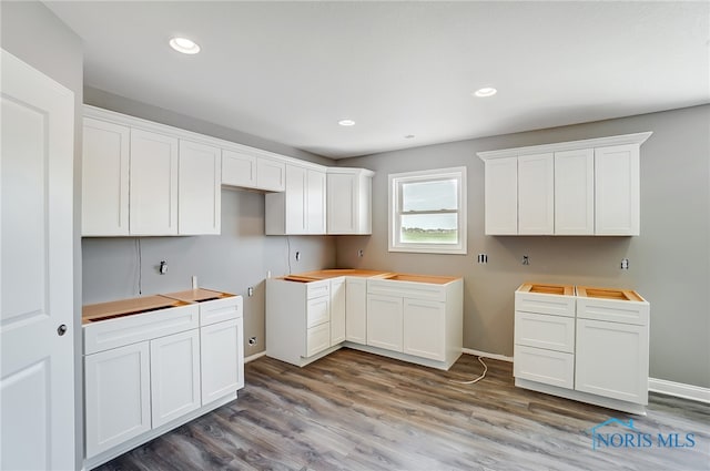 kitchen featuring hardwood / wood-style flooring, butcher block counters, and white cabinets