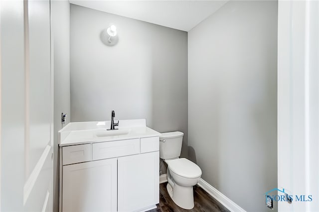 bathroom featuring wood-type flooring, toilet, and vanity