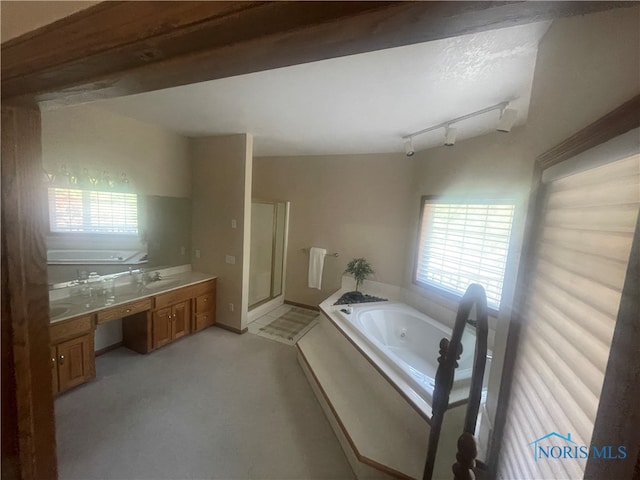 bathroom featuring independent shower and bath, vaulted ceiling, rail lighting, and vanity