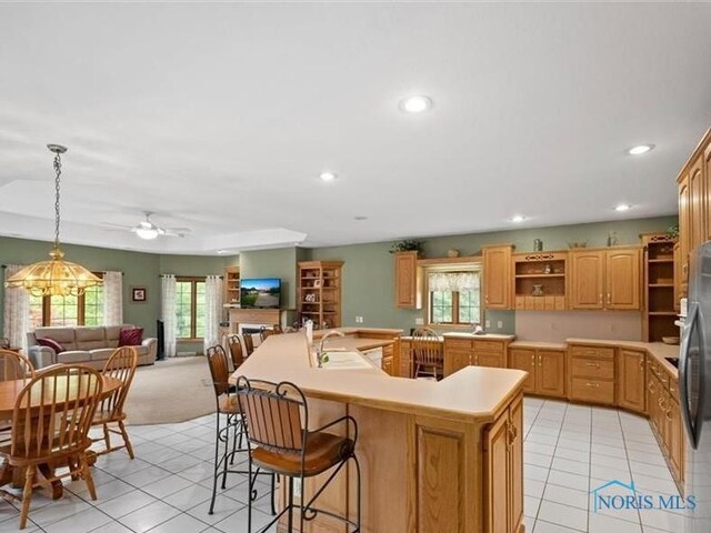 kitchen featuring a center island with sink, sink, decorative light fixtures, light tile patterned floors, and ceiling fan