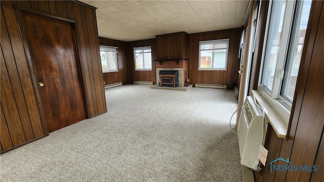 unfurnished living room with a baseboard radiator, wooden walls, and carpet flooring