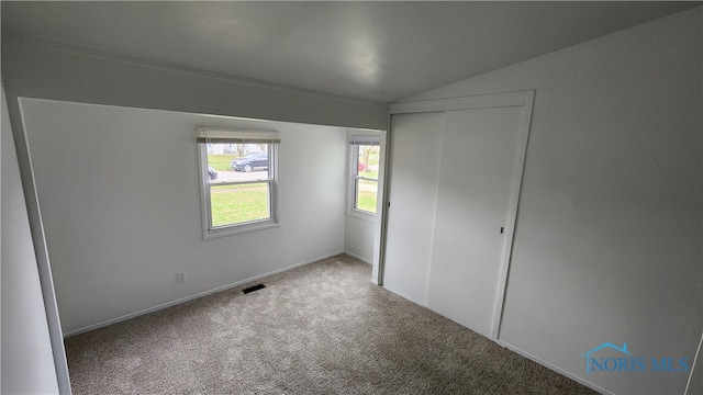 unfurnished bedroom with lofted ceiling, a closet, and carpet flooring