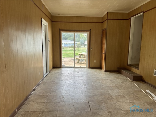 spare room with ornamental molding and wooden walls