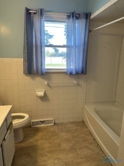 full bathroom featuring vanity, tile walls, washtub / shower combination, and toilet