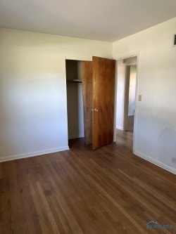 unfurnished bedroom featuring dark hardwood / wood-style flooring and a closet