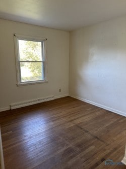 spare room with dark wood-type flooring and baseboard heating