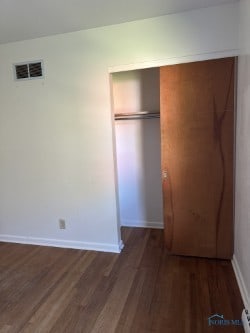 unfurnished bedroom featuring dark wood-type flooring and a closet