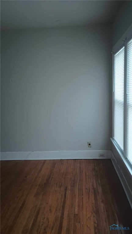 empty room with dark hardwood / wood-style flooring and a healthy amount of sunlight