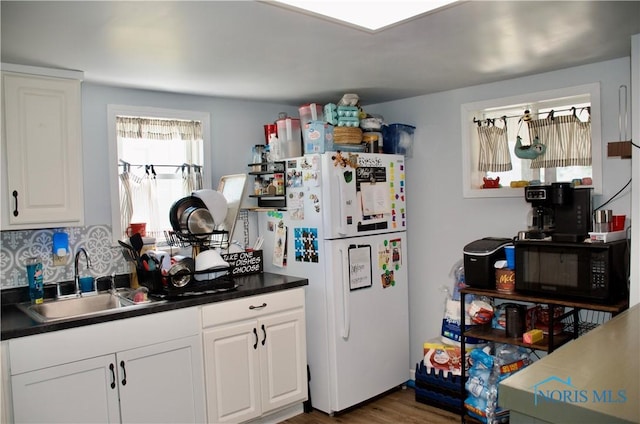 kitchen with dark hardwood / wood-style floors, sink, white fridge, and white cabinets