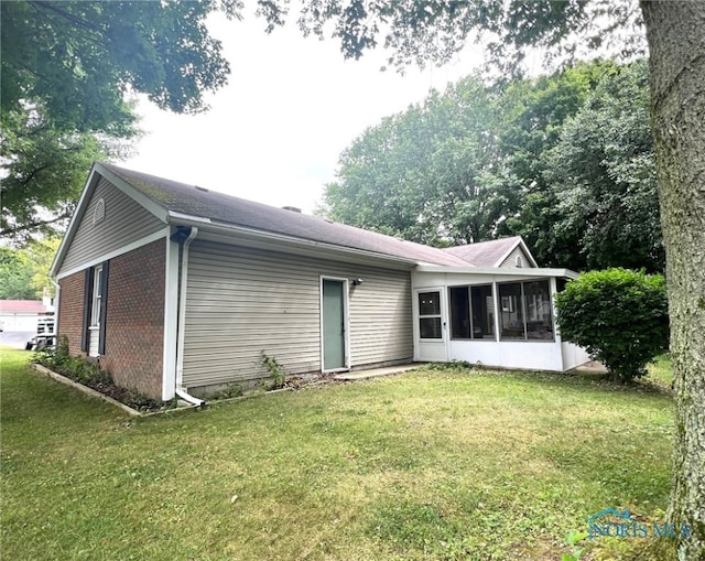 back of property with a sunroom and a yard