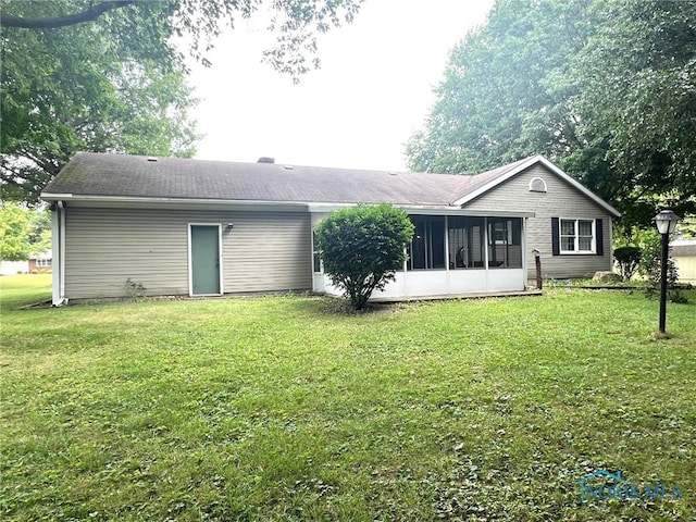 rear view of property featuring a sunroom and a lawn