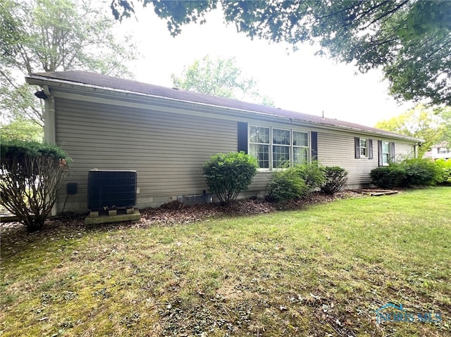 view of side of property with central AC unit and a yard