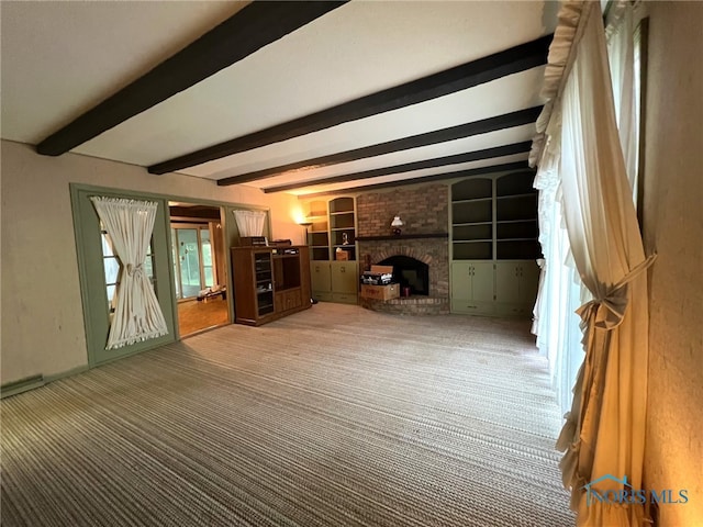 unfurnished living room featuring carpet floors, beam ceiling, a fireplace, and built in shelves