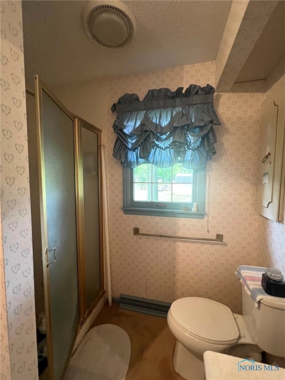 bathroom with toilet, a shower with shower door, and a textured ceiling