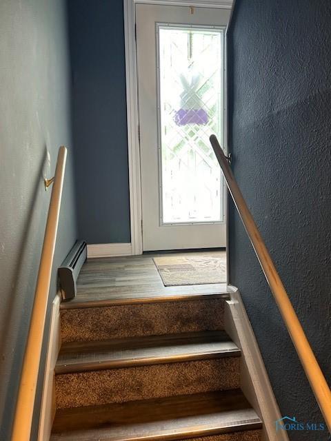 stairs featuring a baseboard heating unit and hardwood / wood-style floors