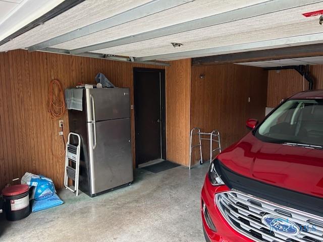 garage featuring stainless steel fridge and wood walls