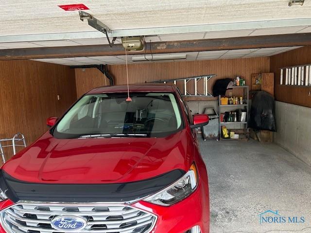 garage with a garage door opener and wood walls