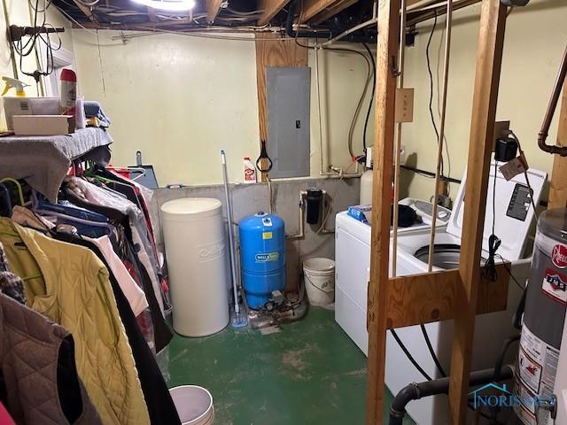 basement featuring washing machine and clothes dryer, electric panel, and water heater