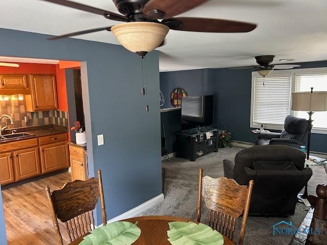 living room with ceiling fan, a baseboard radiator, sink, and light wood-type flooring