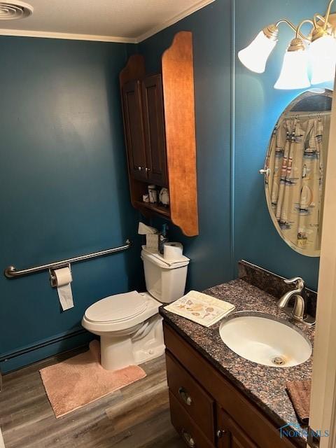 bathroom with toilet, crown molding, baseboard heating, vanity, and hardwood / wood-style floors