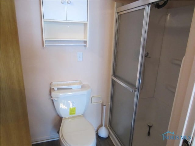 bathroom featuring toilet and a shower with door