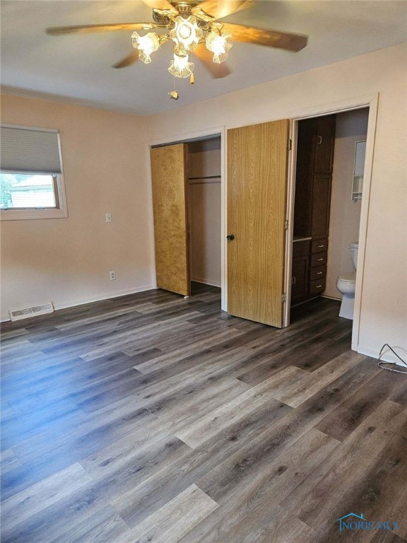 unfurnished bedroom featuring connected bathroom, dark hardwood / wood-style floors, and ceiling fan