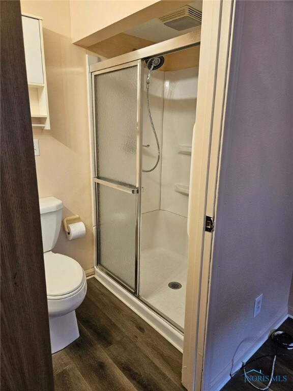 bathroom featuring hardwood / wood-style flooring, toilet, and walk in shower