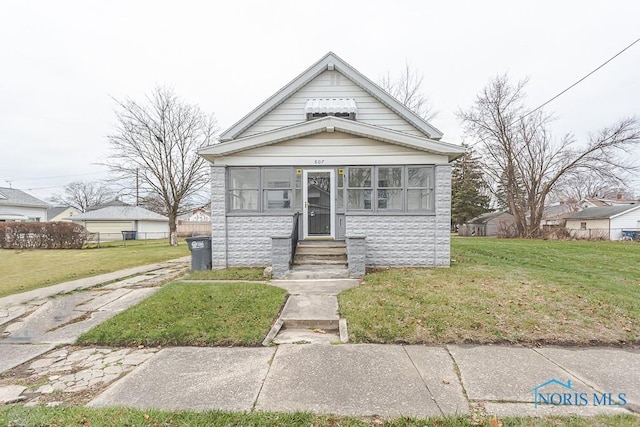 bungalow-style home featuring a front lawn and a sunroom