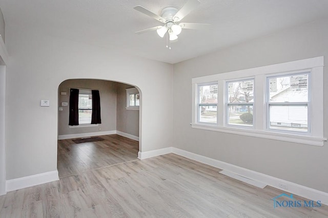 empty room with ceiling fan, a healthy amount of sunlight, and light hardwood / wood-style floors