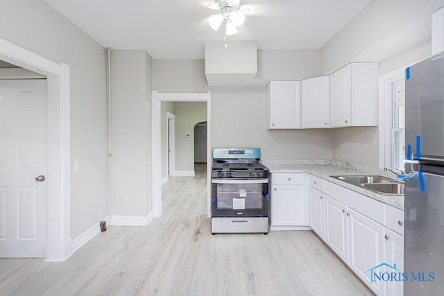 kitchen with appliances with stainless steel finishes, light wood-type flooring, ceiling fan, sink, and white cabinets