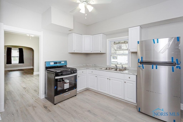 kitchen with appliances with stainless steel finishes, a healthy amount of sunlight, sink, light hardwood / wood-style flooring, and white cabinets