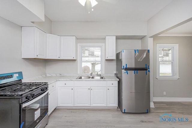 kitchen with sink, ceiling fan, light wood-type flooring, white cabinetry, and stainless steel appliances