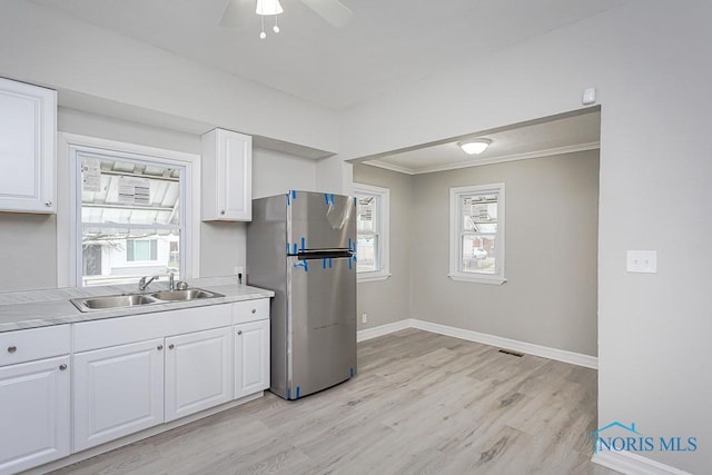 kitchen with white cabinets, sink, light hardwood / wood-style flooring, ceiling fan, and stainless steel fridge