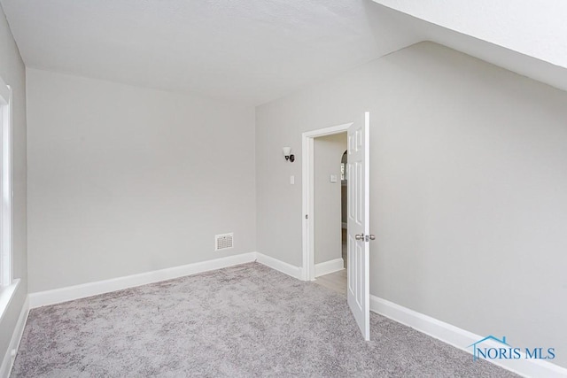 unfurnished room featuring light colored carpet and lofted ceiling