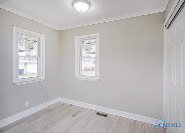 spare room with a textured ceiling, light hardwood / wood-style flooring, and ornamental molding